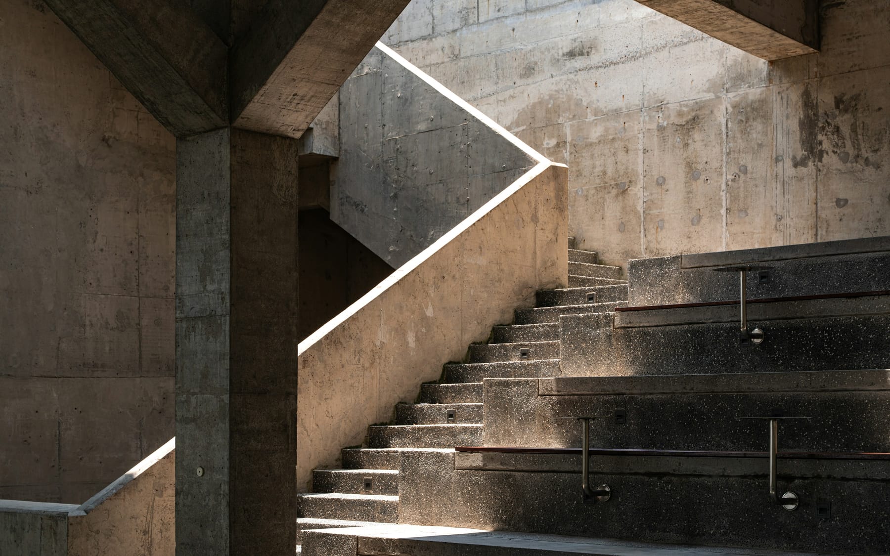 A concrete stairwell lit by a continuous recessed light line running along the wall.