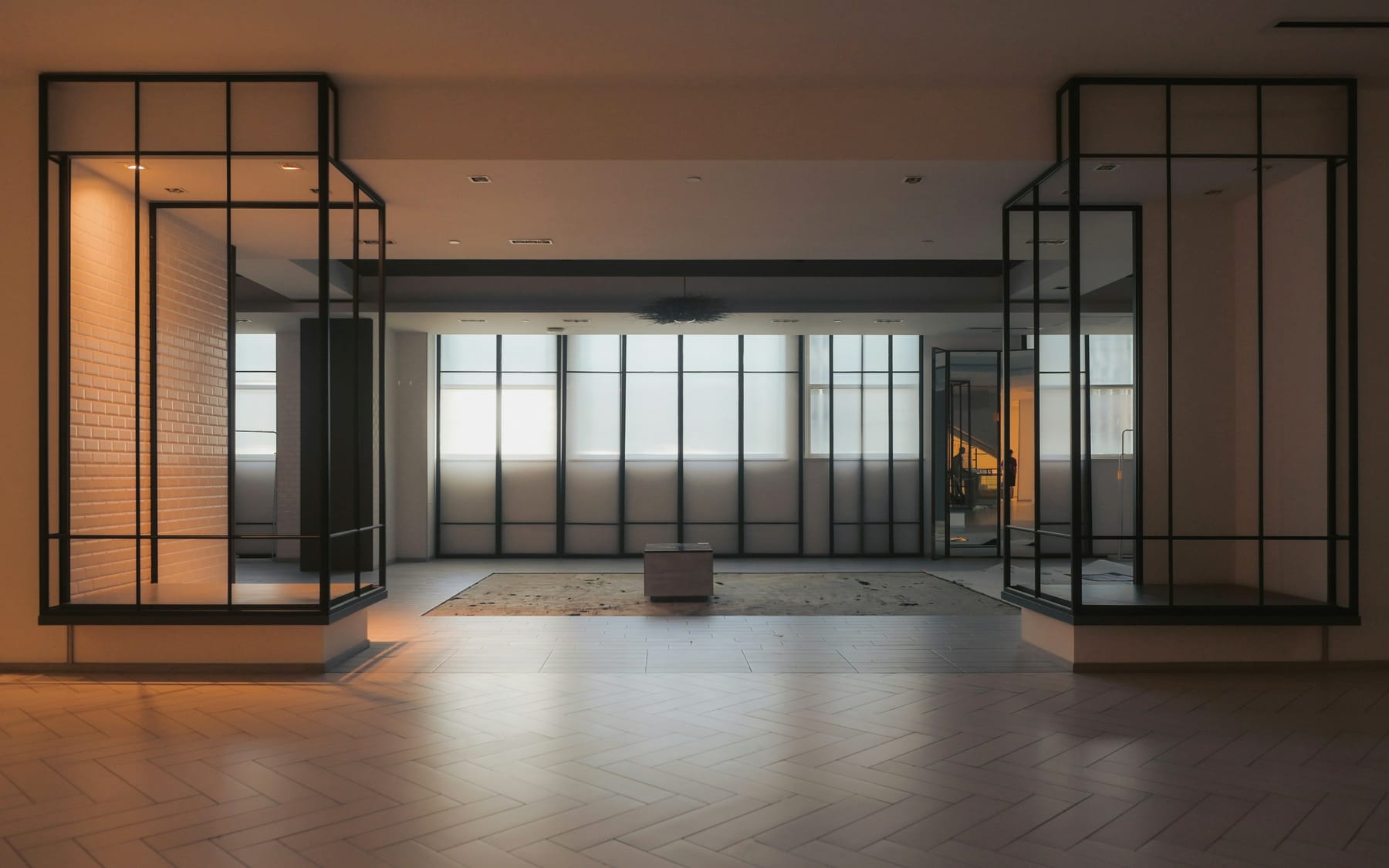 An open interior with black-framed glazed screens and a pale timber floor.